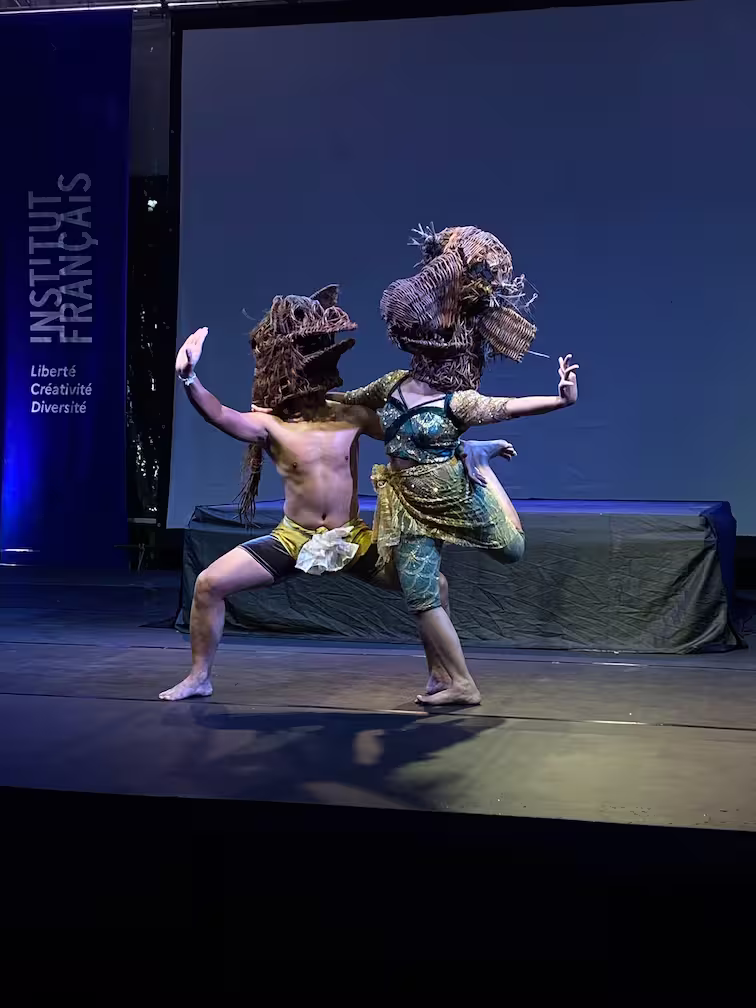 On stage, two classical Khmer dancers wearing masks made by the artist Khvay Samnang